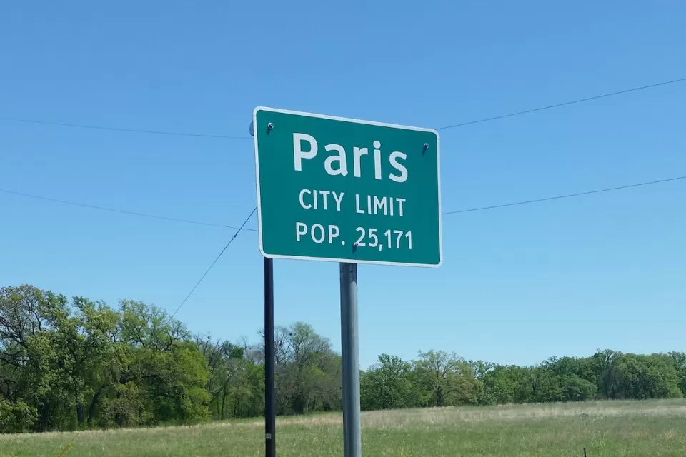 Green Paris Texas city limit sign with population.